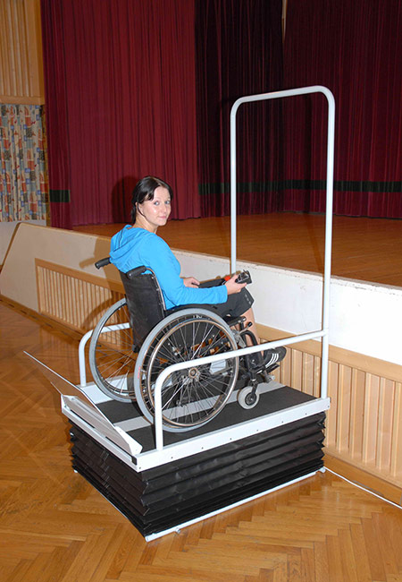 Eine junge Dame benutzt mit ihrem Rollstuhl den LIFTBOY, um die Bühne zu erreichen