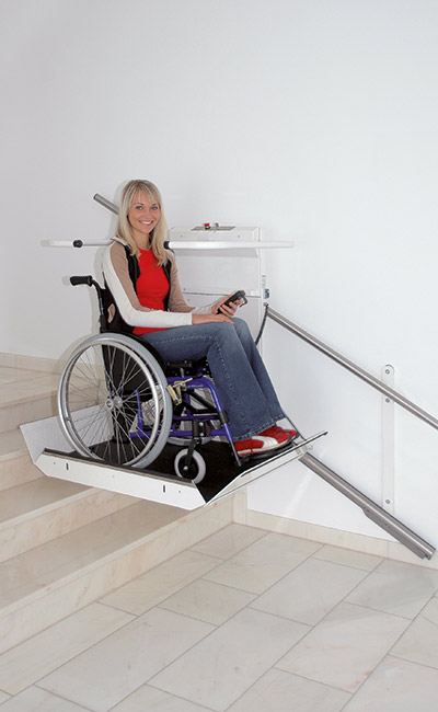 Eine junge Dame benutzt mit ihrem Rollstuhl den Plattformtreppenlift DELTA